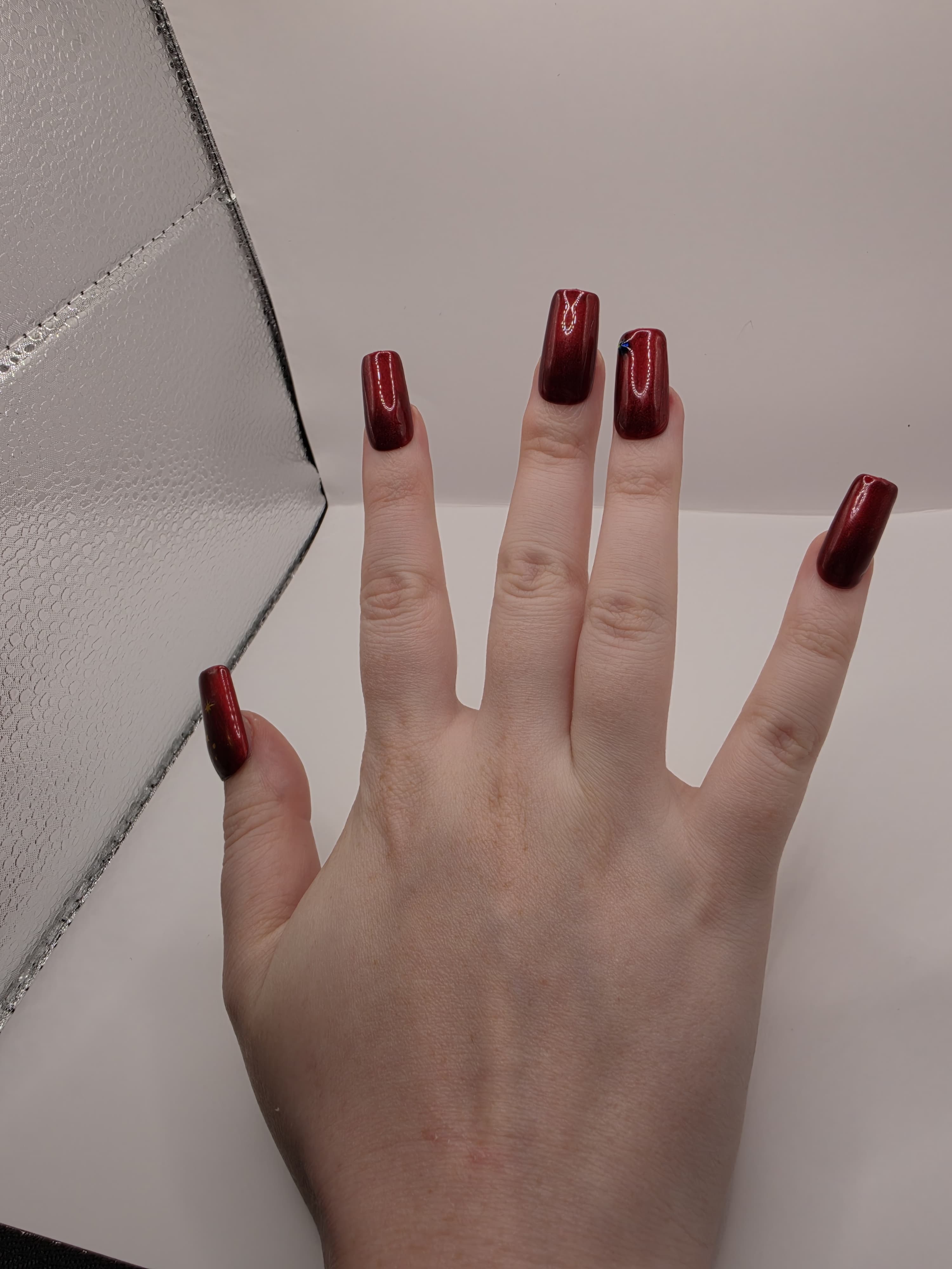 #59 Base Coat: Red shimmer base coat with black opalescent gem on ring fingers and gold moon and star motiff on the thumbs featured on medium square nails