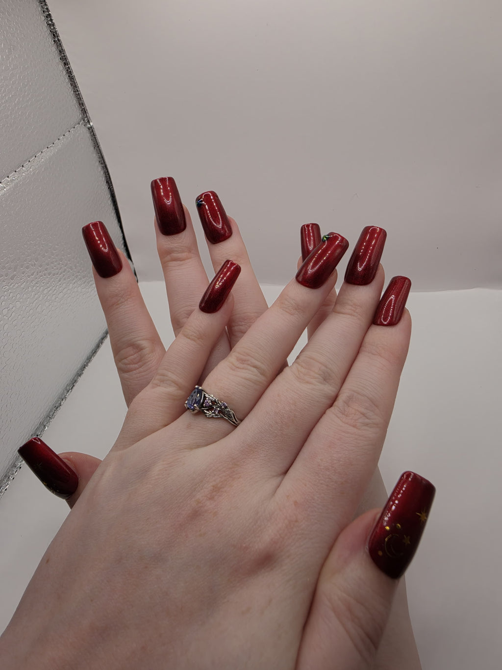#59 Base Coat: Red shimmer base coat with black opalescent gem on ring fingers and gold moon and star motiff on the thumbs featured on medium square nails