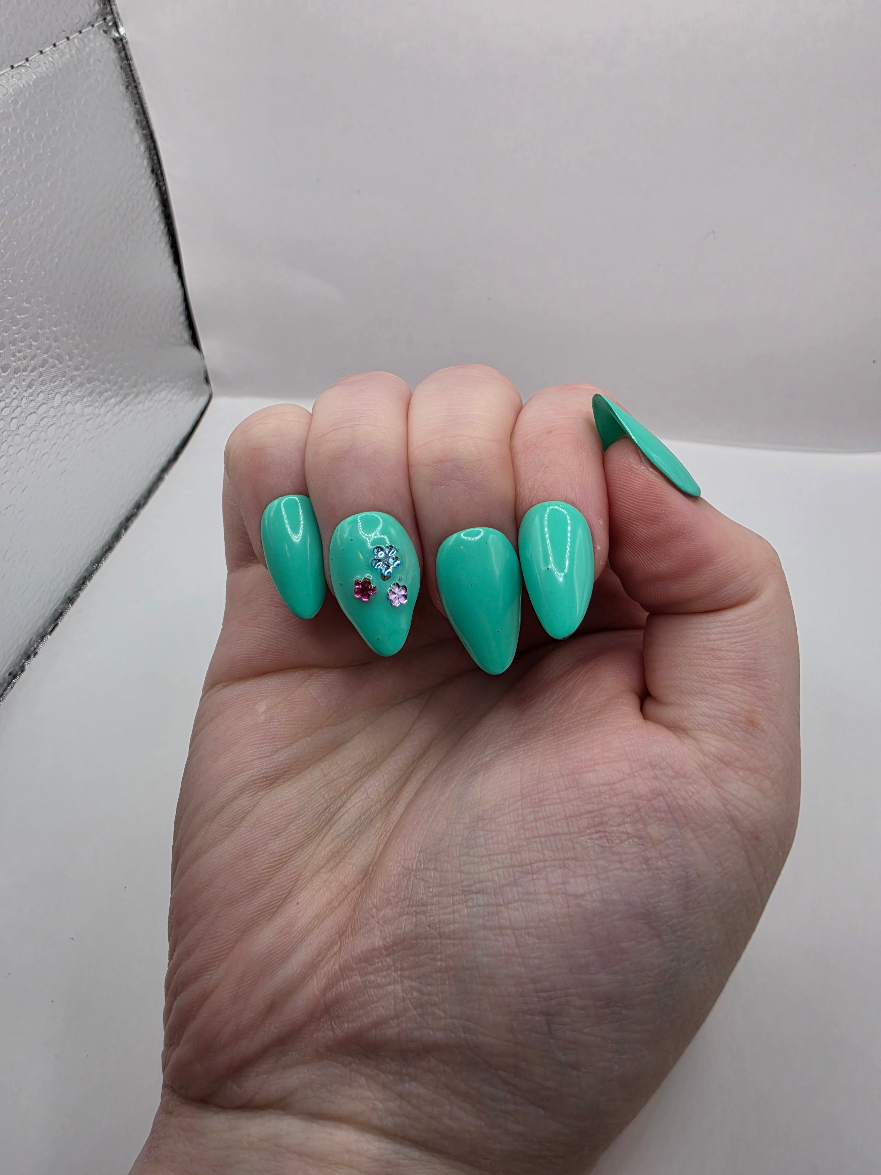 #147 Base Coat: A summery sensational turquoise with three different colored flower charms (purple, light blue, and hot pink) inbedded into the accent ring finger nail featured on short almond nails